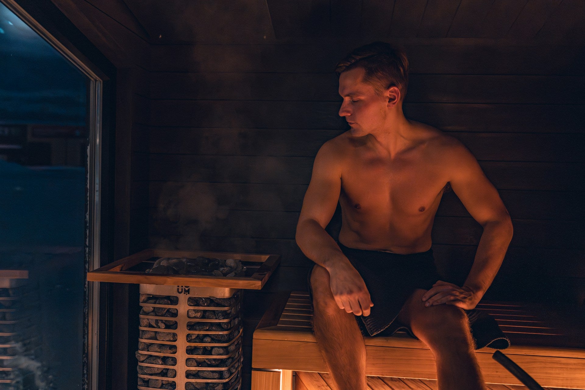 Man sitting in a sauna smoking a cigarette.