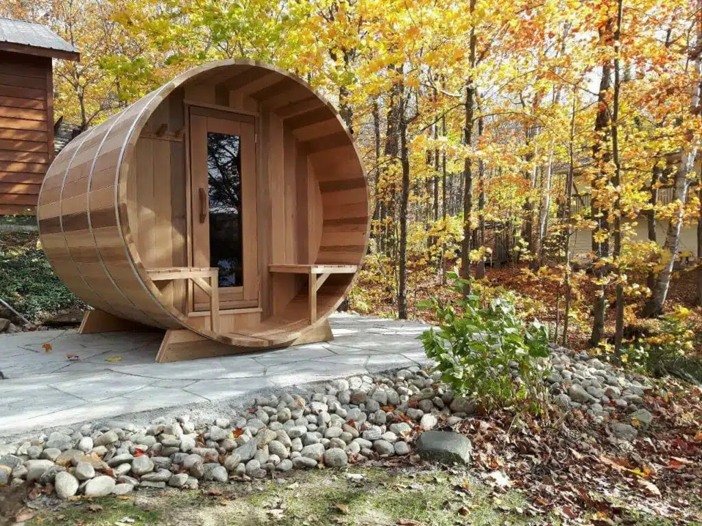 Wooden barrel-shaped structure in a forest setting with autumn foliage.