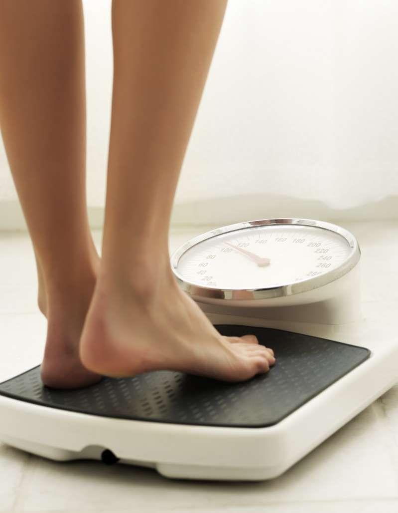 Person standing on a digital weight scale with a white background