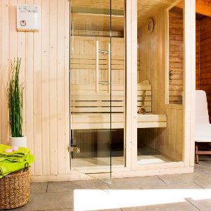 Wooden sauna with glass door and interior details, featuring a plant and towel.