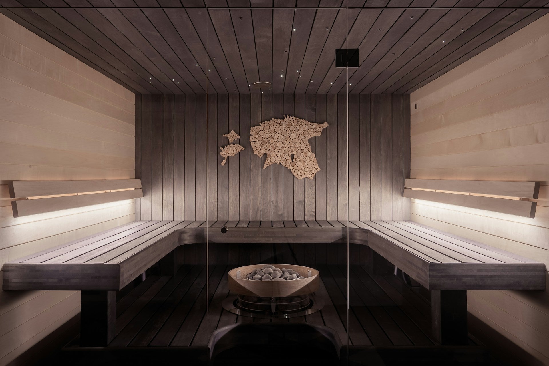 Interior of a modern sauna with wooden benches and wall decor.